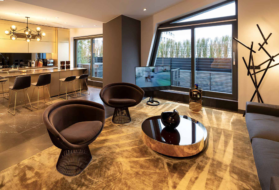 Living room and kitchen on an open space, featuring a kitchen isle with four chairs and a big chandelier. kitzig design studios Kitzig Design Studios- From Germany to the World Interior Apartment Berlin 02 2 1