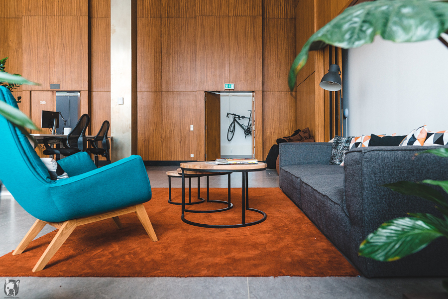 Otto Von Berlin-Interior Design Kleiderkreisel living space of the office, with a grey sofa, a blue armchairs and 3 round tables.  otto von berlin Otto Von Berlin-Interior Design Otto Von