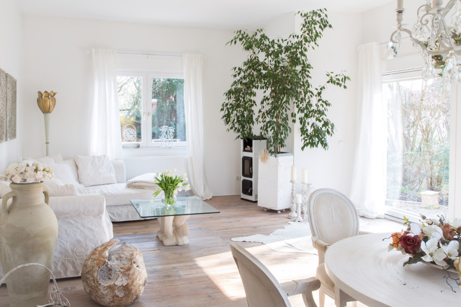 Einfamilienhaus living room in white tones with some flowers around the room. All the furniture is white, or in glass, like the center table that has a glass over a white sulptured structure.  the stilschmiede berlin The Stilschmiede Berlin- Interior Design Inspirations BB Inspiartiosn and Ideas stilschmiede berlin portfolio haus in bohnsdorf 01