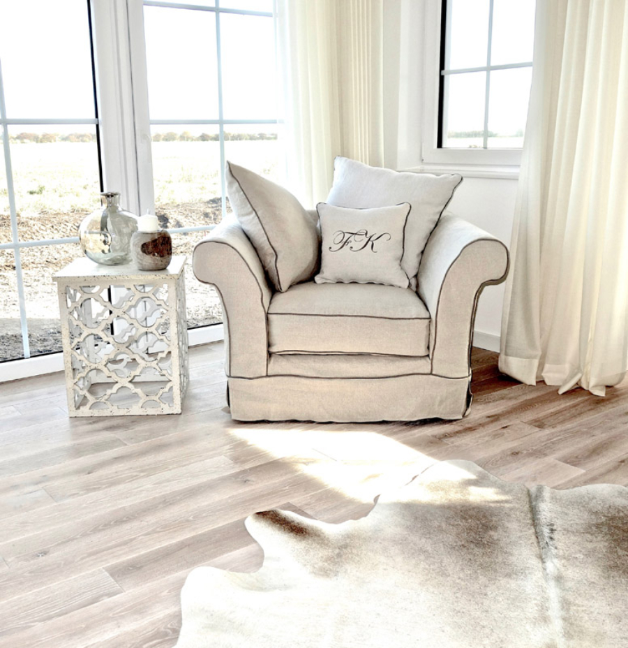 Haus auf Rügen reading corner with a white armchair that has a pillow on top, a white side table wih a candel and a vase on top, also in these tones. the stilschmiede berlin The Stilschmiede Berlin- Interior Design Inspirations BB Inspiartiosn and Ideas stilschmiede berlin portfolio haus ruegen 01