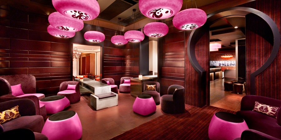 Dark living room with wood walls and pink details accompanied with custom velvet and leather upholstery. 
 hba HBA – The Best Interior Design Projects in Dubai HBA4