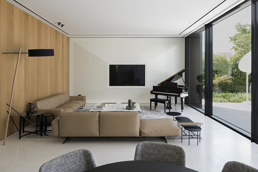 A open living room with a wood wall completed with some bespoke upholstery, a marble center table and a black piano.  vshd design VSHD Design – Minimalist Interior Designs Inspirations Webp