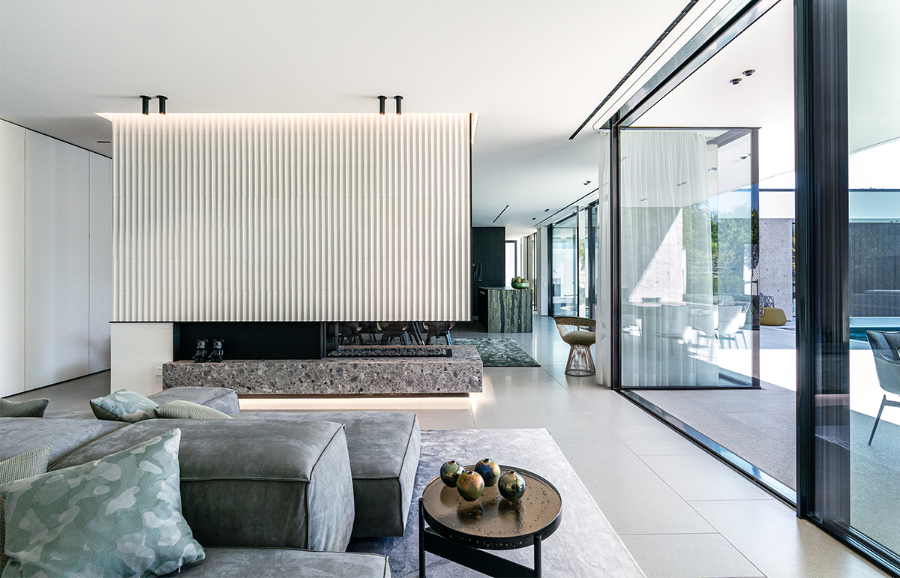modern interior design ideas, LINEA NERA project living room, with a fireplace, glass walls to the outside, a grey sofa and a round side table next to the sofa.  modern interior design ideas Reimann Architecture: Modern Interior Design Ideas LineaNera privatehaus  Reimann Architecture Modern Interior Design Ideas