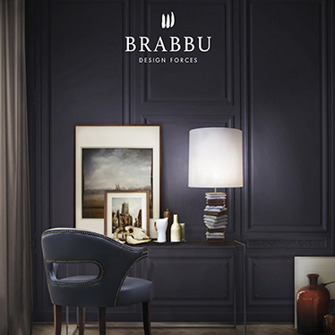 A mid century modern home office décor with a contemporary desk, a blue desk chair, a modern table lamp and a beige patterned rug. The dark wallpaper connects all these custom made furniture pieces.